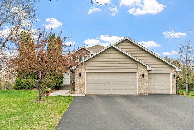 view of front of home featuring aphalt driveway, fence, brick siding, a garage, and a front yard