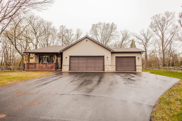 single story home with a porch, brick siding, fence, aphalt driveway, and an attached garage