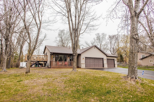 view of front of home with a front lawn, a wooden deck, a garage, a shingled roof, and aphalt driveway