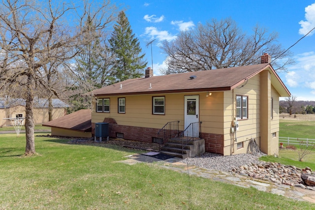 rear view of property featuring fence, a chimney, a yard, and a shingled roof