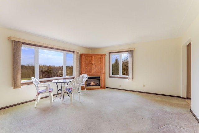 interior space featuring baseboards, light carpet, and a healthy amount of sunlight