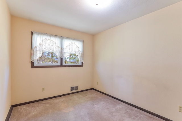 carpeted spare room featuring visible vents and baseboards