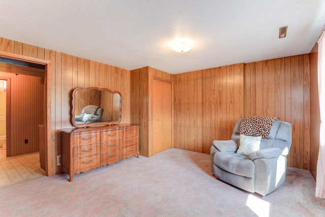 sitting room featuring wood walls and carpet flooring