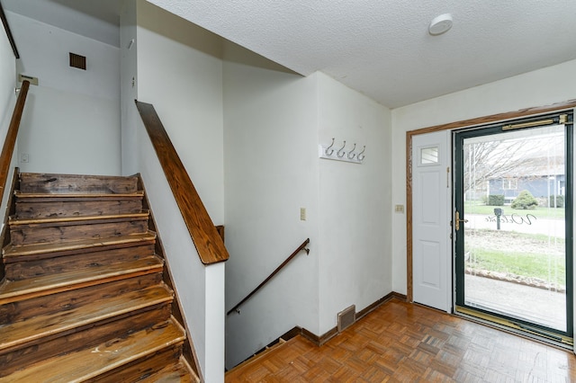 entrance foyer with baseboards, a textured ceiling, and visible vents