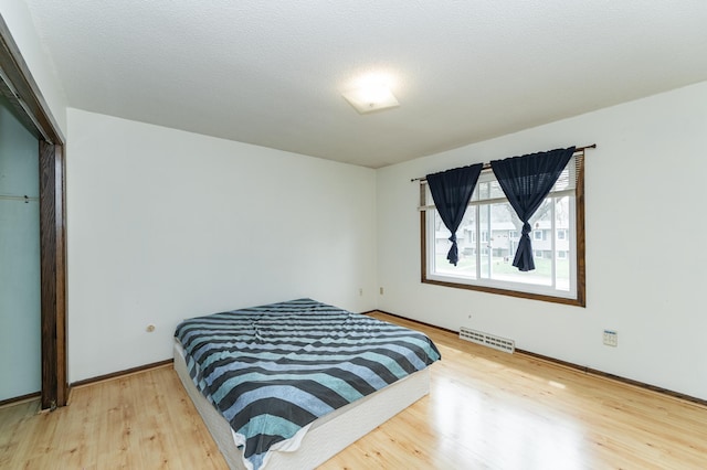 bedroom featuring visible vents, baseboards, and wood finished floors