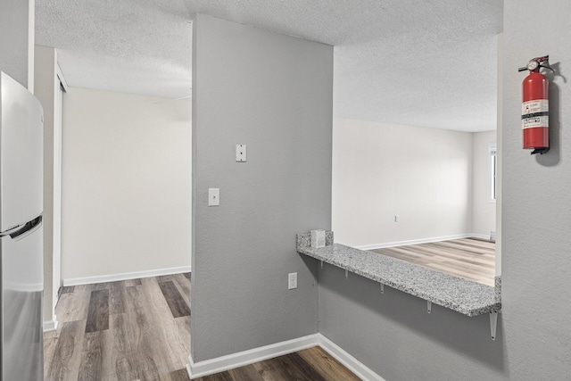 221 Grand Ave W Unit 111, South Saint Paul, MN 55075 - interior space featuring freestanding refrigerator, a textured ceiling, baseboards, light stone counters, and wood finished floors