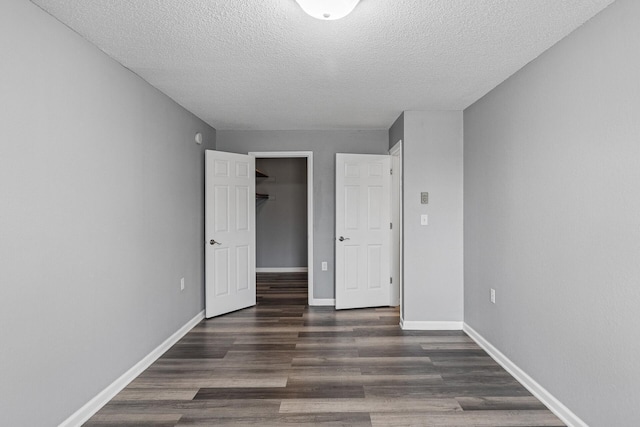 221 Grand Ave W Unit 111, South Saint Paul, MN 55075 - unfurnished bedroom featuring a closet, a textured ceiling, dark wood-style flooring, and baseboards