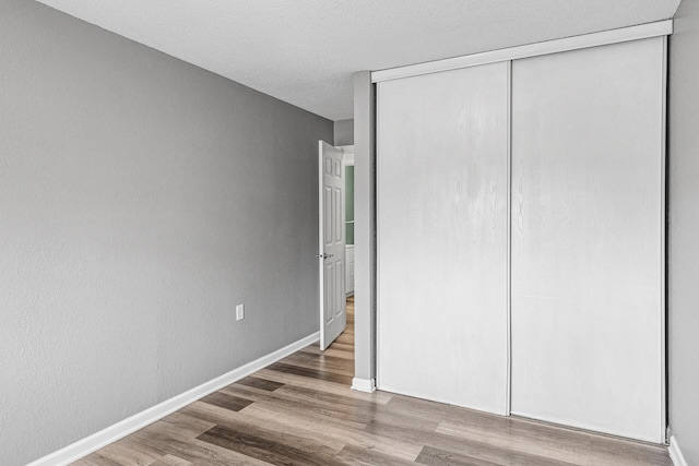 221 Grand Ave W Unit 111, South Saint Paul, MN 55075 - unfurnished bedroom with wood finished floors, a closet, baseboards, and a textured ceiling