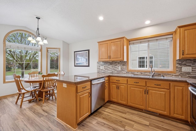 kitchen featuring a sink, stainless steel appliances, a peninsula, backsplash, and vaulted ceiling