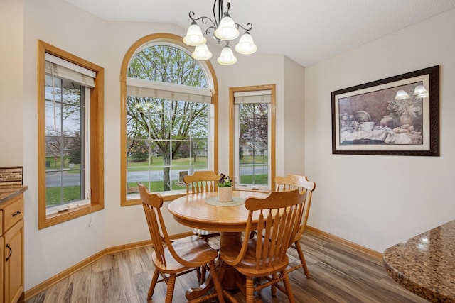 dining area featuring an inviting chandelier, light wood finished floors, lofted ceiling, and baseboards