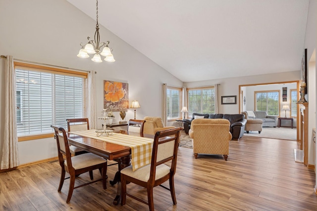 dining area featuring high vaulted ceiling, light wood-type flooring, and a notable chandelier