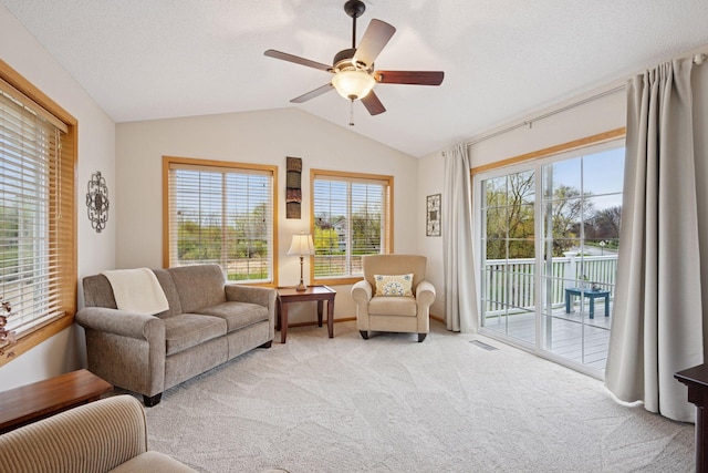 living area featuring a healthy amount of sunlight, carpet floors, ceiling fan, and vaulted ceiling