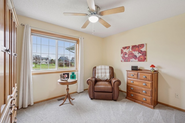 living area featuring baseboards, a ceiling fan, and light carpet