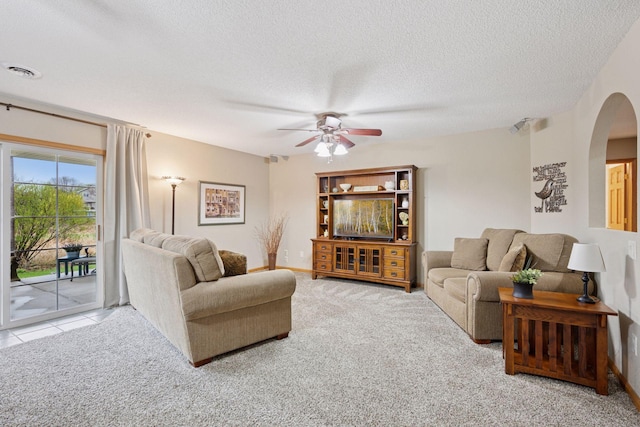 living area featuring arched walkways, a ceiling fan, carpet floors, and visible vents