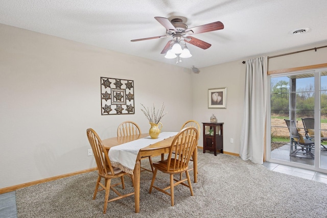 dining space featuring light carpet, a textured ceiling, a ceiling fan, baseboards, and visible vents