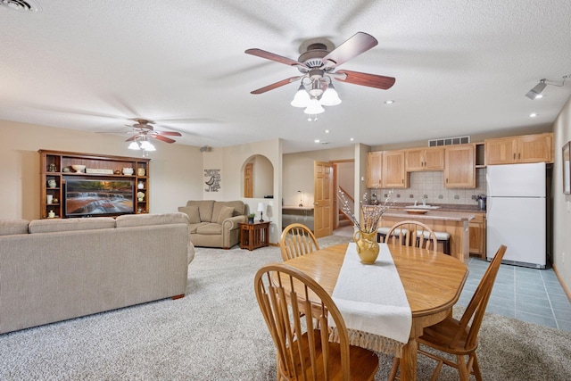 dining space featuring ceiling fan, a textured ceiling, light colored carpet, visible vents, and stairway