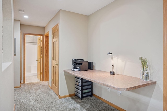 carpeted office with baseboards and built in desk
