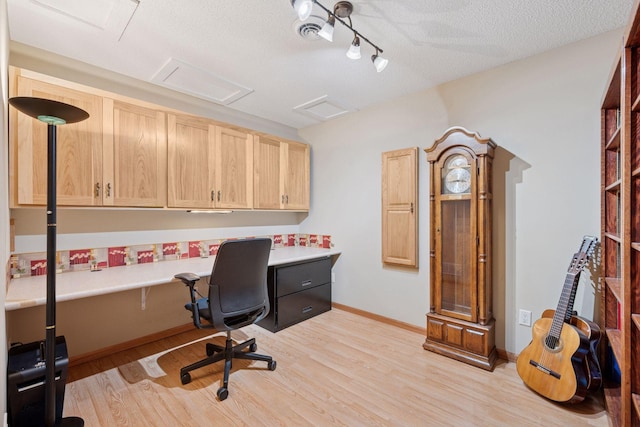office space featuring baseboards, attic access, light wood-type flooring, and a textured ceiling