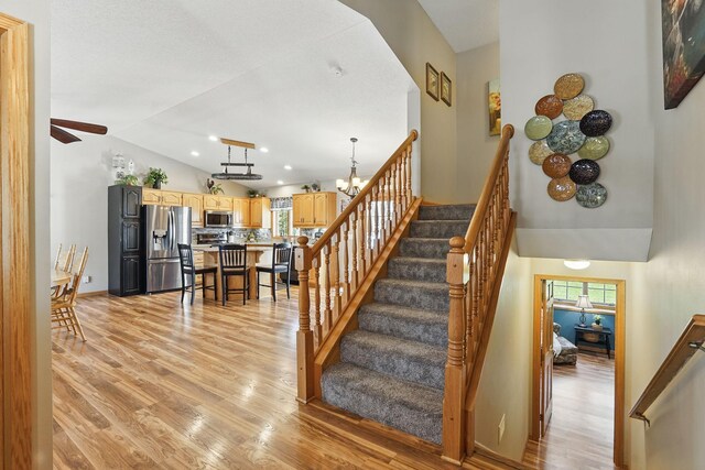 staircase with high vaulted ceiling, baseboards, a ceiling fan, and wood finished floors