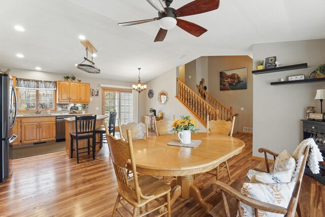 dining space featuring ceiling fan with notable chandelier, recessed lighting, lofted ceiling, light wood-type flooring, and stairway