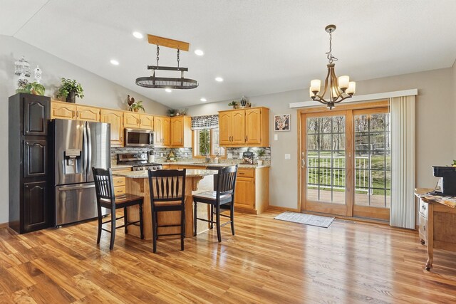 kitchen featuring decorative backsplash, vaulted ceiling, light countertops, stainless steel appliances, and light wood-style flooring