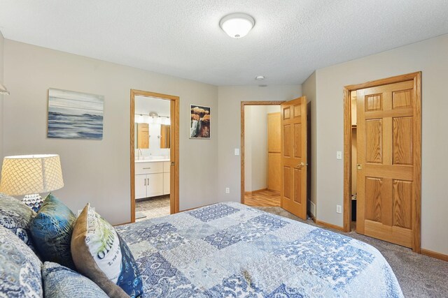 bedroom with connected bathroom, a textured ceiling, baseboards, and carpet