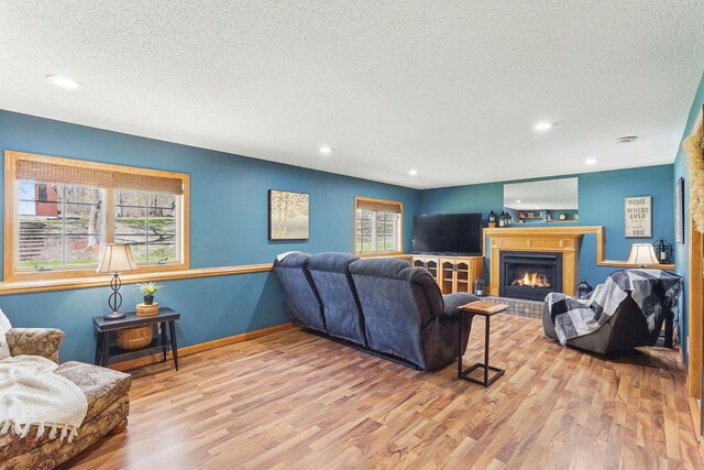 living area with a fireplace, a textured ceiling, and wood finished floors