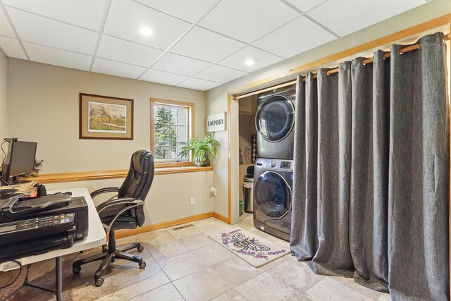 home office with stacked washer / drying machine, a paneled ceiling, baseboards, light tile patterned floors, and visible vents