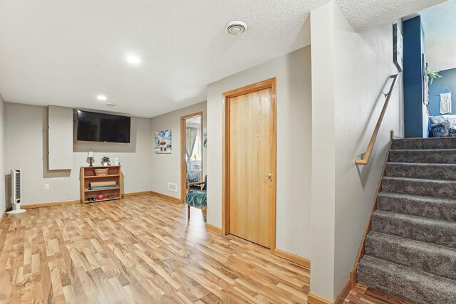 below grade area with stairs, heating unit, light wood-style floors, baseboards, and recessed lighting