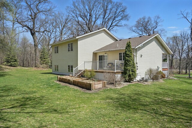 rear view of property with a lawn, a wooden deck, and a garden
