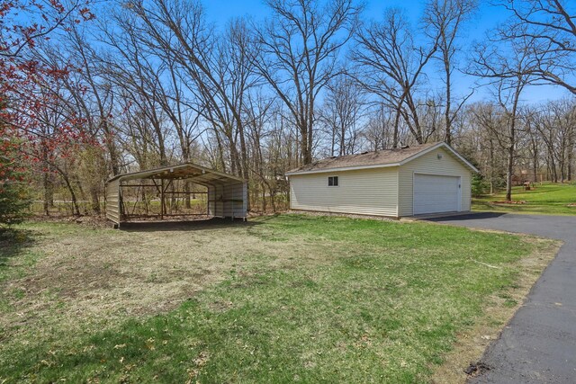 view of yard with an outdoor structure, a garage, aphalt driveway, and a carport