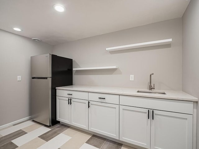 kitchen featuring recessed lighting, freestanding refrigerator, open shelves, white cabinets, and a sink