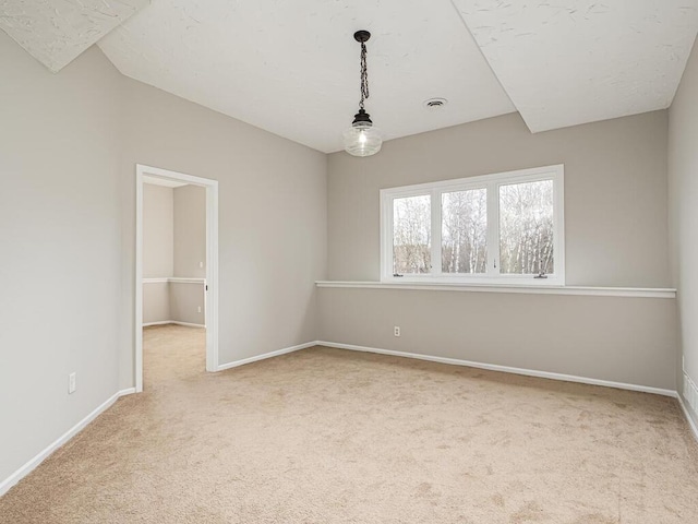 unfurnished room with carpet, visible vents, and baseboards