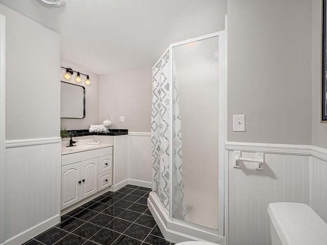 full bath featuring vanity, a wainscoted wall, a shower stall, and tile patterned floors