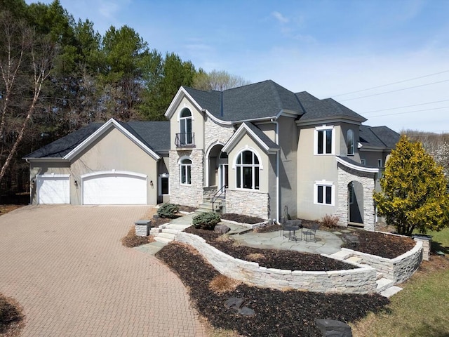 view of front of home featuring stucco siding, driveway, an attached garage, and stone siding
