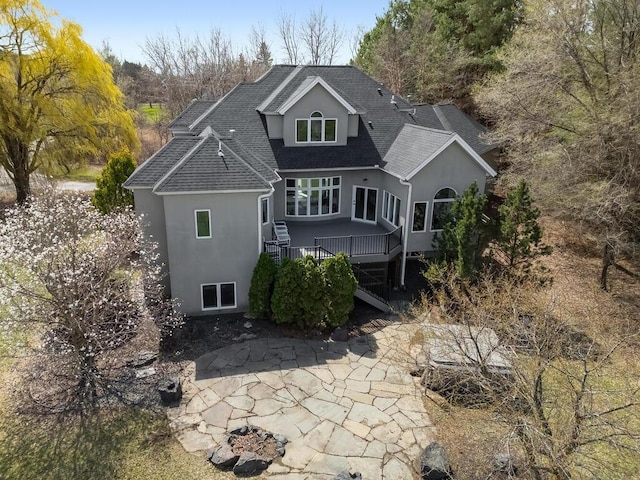 back of property featuring a patio, a deck, stucco siding, and roof with shingles