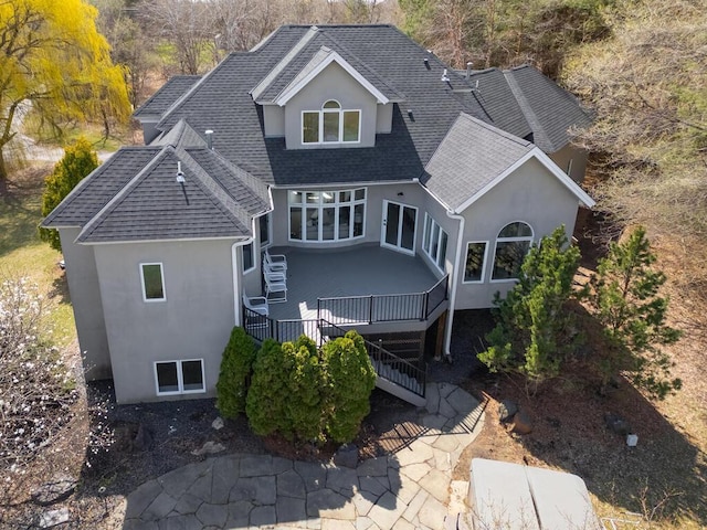 back of house with stairs, a wooden deck, a patio area, roof with shingles, and stucco siding