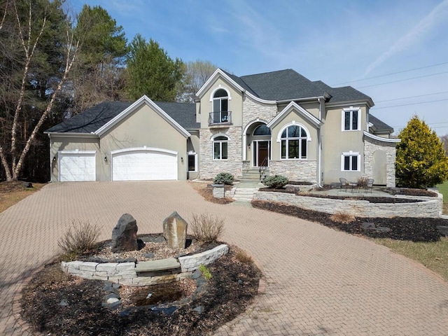 view of front of home featuring stucco siding, decorative driveway, a garage, and stone siding