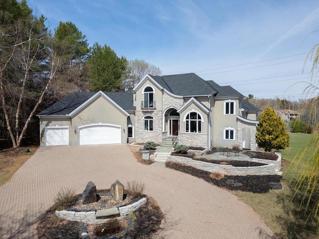 view of front of home with decorative driveway, stone siding, stucco siding, and an attached garage