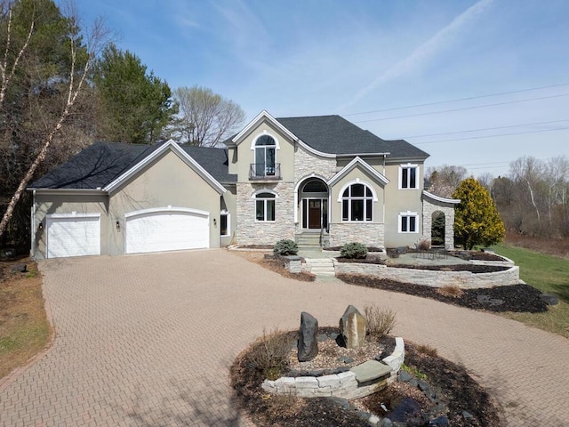 view of front facade featuring a shingled roof, a garage, decorative driveway, stone siding, and stucco siding