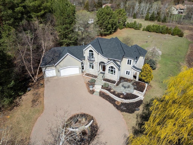 view of front of home featuring driveway, a garage, stucco siding, and stone siding