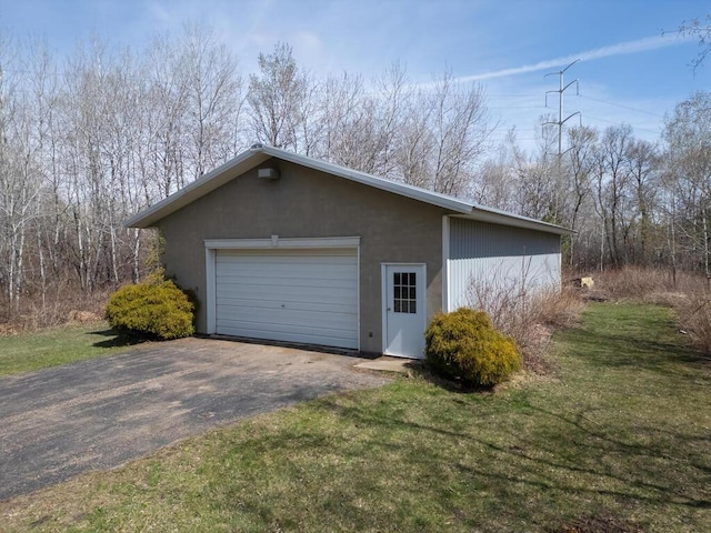 view of property exterior with an outdoor structure, a detached garage, and a yard
