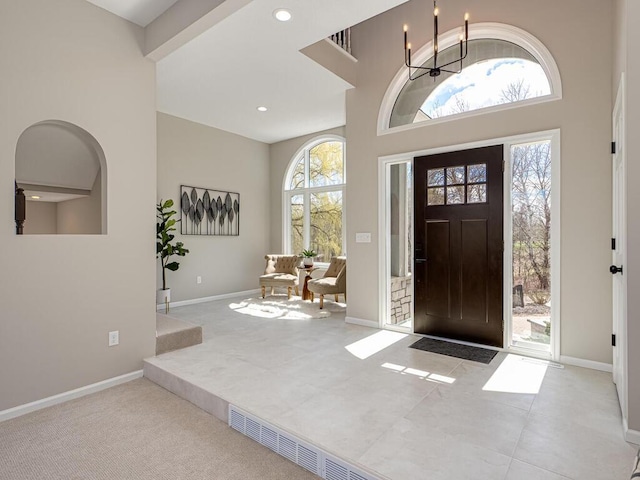foyer with a towering ceiling, recessed lighting, a chandelier, and baseboards