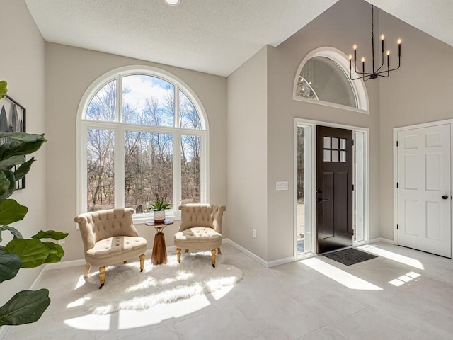 entryway with a textured ceiling, a chandelier, and baseboards