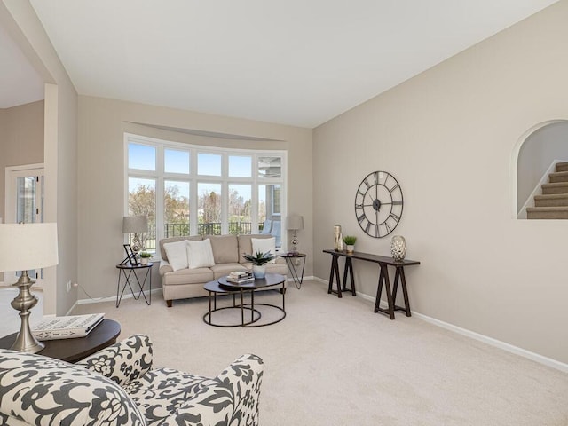 carpeted living room featuring stairway and baseboards