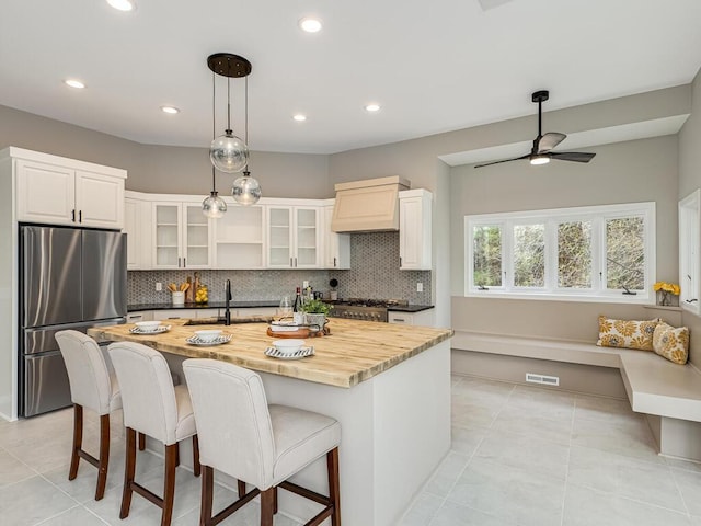 kitchen featuring freestanding refrigerator, ceiling fan, backsplash, a kitchen bar, and a sink