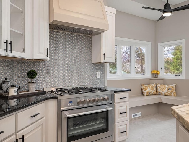 kitchen featuring tasteful backsplash, visible vents, a healthy amount of sunlight, high end stainless steel range, and custom exhaust hood