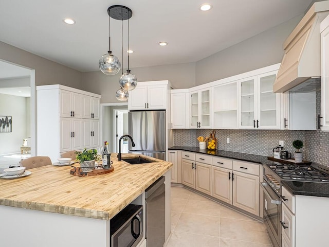 kitchen with light tile patterned floors, stainless steel appliances, backsplash, and a sink