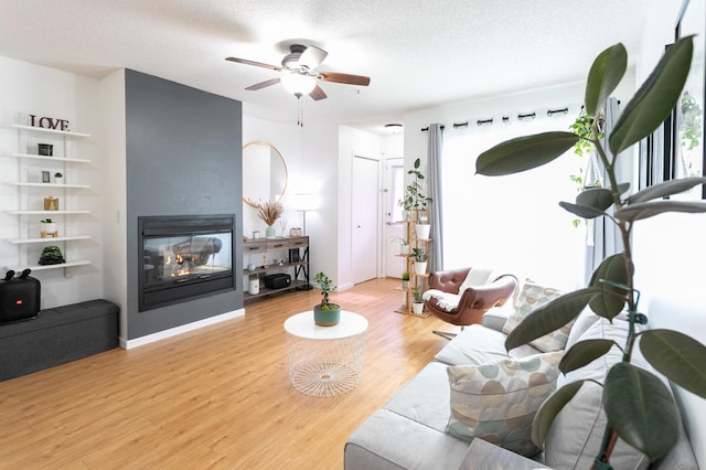 2225 Ranchview Ln N Unit 9, Plymouth, MN 55447 - living area with wood finished floors, ceiling fan, a multi sided fireplace, and a textured ceiling