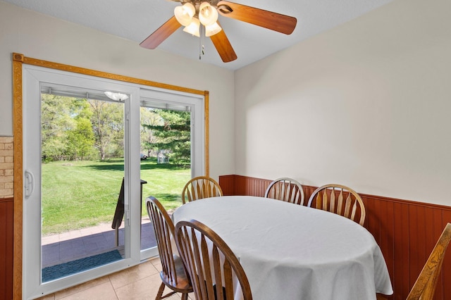 7830 Country Ln, Lino Lakes, MN 55014 - dining space with wainscoting, plenty of natural light, a ceiling fan, light tile patterned floors, and wood walls